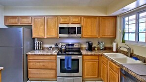 A kitchen with wooden cabinets, stainless steel appliances, granite countertops, and a skylight.