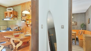 A modern kitchen with wooden cabinets, a dining table, and a large mirror.