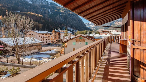 A wooden balcony with a view of a mountain village and snow-covered buildings.