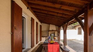 A covered outdoor dining area with a table and benches, a wooden ceiling, and a view of a street. - L'Albizia by Interhome (Gujan-Mestras)