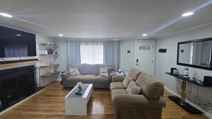 Ein Wohnzimmer mit einer Couch, einem Couchtisch, einem Fernseher und einem Kamin.
