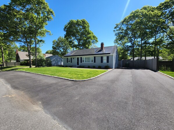 A residential street with a house featuring a sloped roof and solar panels.