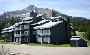 Un hôtel à plusieurs étages, doté d’une architecture moderne, avec des balcons et de grandes fenêtres, et qui se distingue par son emplacement au pied d’une chaîne de montagnes.