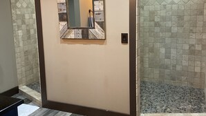 Une salle de bain avec un miroir en bois, des murs carrelés et un espace douche.