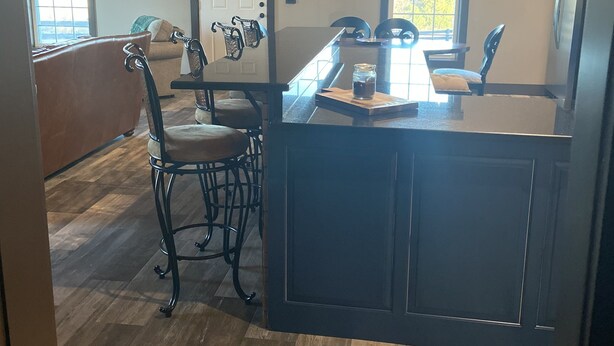 Une cuisine dotée d’un îlot central, d’un plancher en bois et d’un coin repas avec des chaises et un banc.