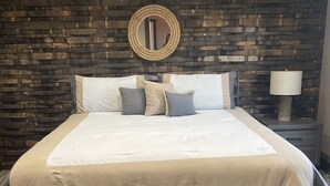 Une chambre avec un grand lit, un mur en bois foncé et un miroir rond.