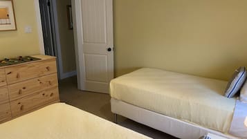 Un dormitorio con un aparador de madera, una cama con almohadas y una puerta que da a otra habitación.