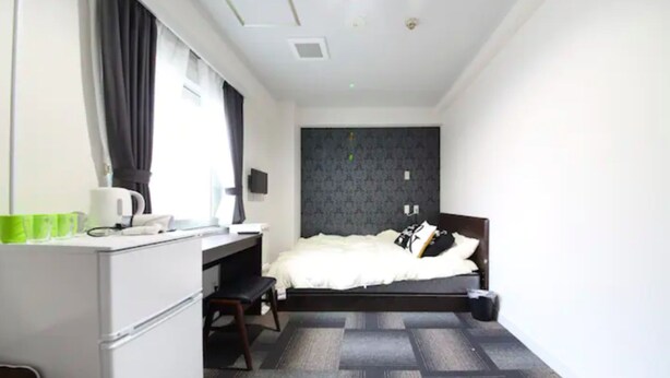 A compact hotel room with a bed, a desk, and a chair.