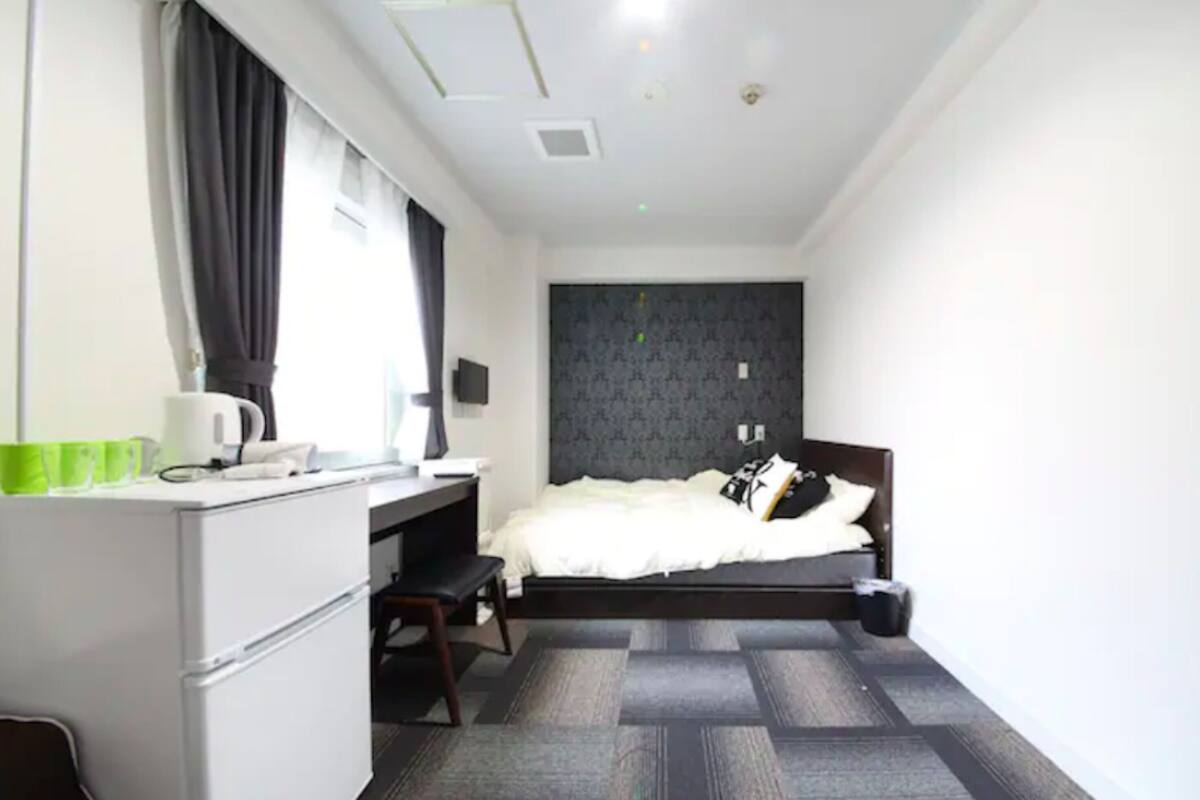 A compact hotel room with a bed, a desk, and a chair.