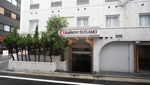 A hotel with a sign reading "EXsaison SUGAMO" and a modern brick facade.