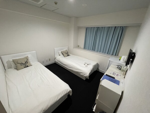 A hotel room with two single beds, a small desk with a printer, and a window with curtains. - Exsaison Sugamo (Tokyo)