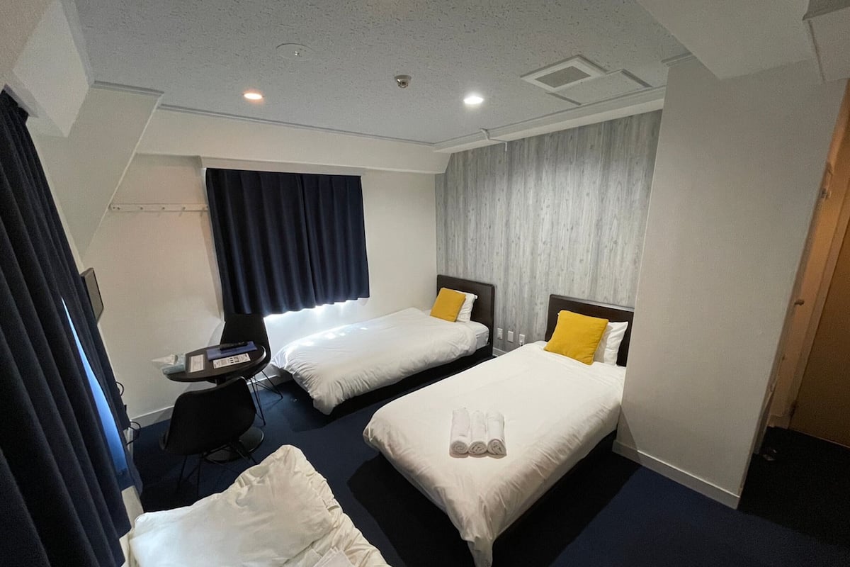 A hotel room with two beds, a desk, and a chair.