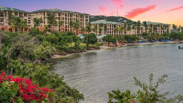 A hotel with multiple floors, a waterfront view, and lush greenery.