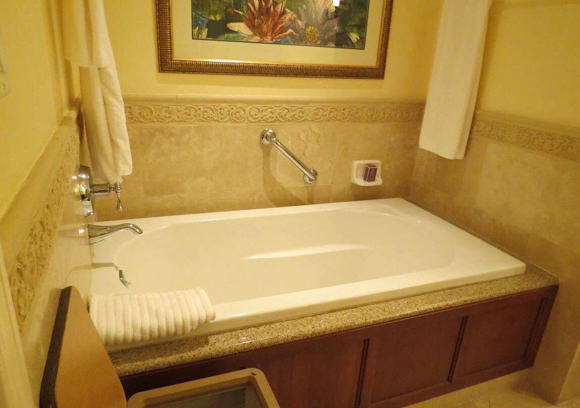 Une salle de bain avec une grande baignoire, un porte-serviettes et un tableau encadré au mur.