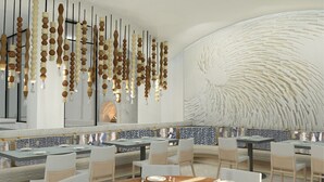 Interior moderno de restaurante com ornamentos de madeira pendurados, parede estampada e área de estar com mesas e cadeiras.