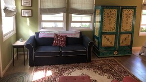 A living room with a dark blue sofa, a patterned rug, and a green cabinet with decorative panels. - Charming guest house on 1.5 acre lake front property (Green Lake)
