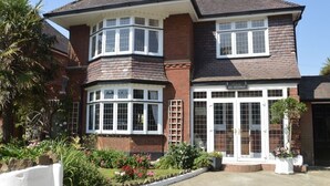 A two-story brick house with a bay window and a front door with glass panels. - Large four bedroom home near country walks & beach (Shanklin)