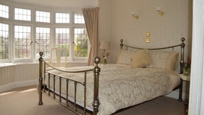 A bedroom with a large window, a bed with a headboard, and a nightstand with a lamp. - Large four bedroom home near country walks & beach (Shanklin)