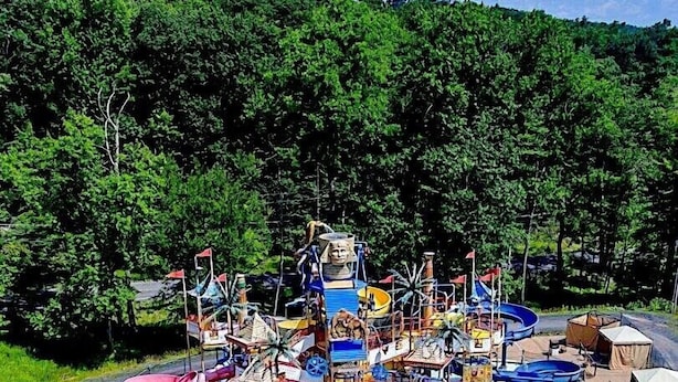 Parque acuático con múltiples toboganes y piscinas, rodeado de árboles.