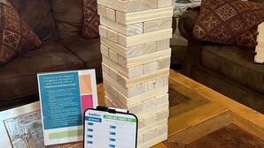 Una torre de Jenga de madera sobre una mesa de centro, junto con las instrucciones del juego y un letrero de bienvenida.