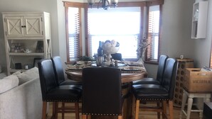 A dining area with a round table, four chairs, and a chandelier. - Cabin with Spa and Arcades 7 mins to Ski Resort (Running Springs)