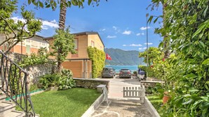 A residential area with a stone staircase, a grassy lawn, and a view of a body of water and mountains. - Casa Tamè - Pieds dans l'eau, Melide, Switzerland (Melide)