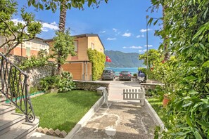 A residential area with a stone staircase, a grassy lawn, and a view of a body of water and mountains. - Casa Tamè - Pieds dans l'eau, Melide, Switzerland (Melide)