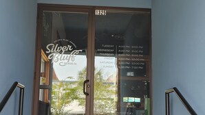 Ein Laden mit Glastür, einem Schild für 'Silver Bluff Brewing Co.' und einer angebrachten Anzeige der Öffnungszeiten.