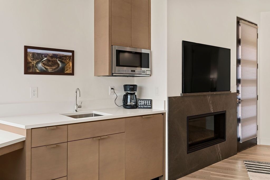 A modern kitchen with a built-in microwave, a coffee maker, and a flat-screen TV.