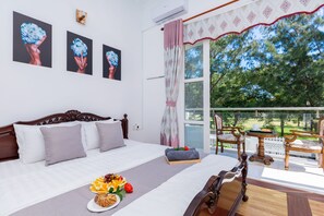 Een hotelkamer met een groot bed, een balkon met een tafel en stoelen, en kunst aan de muren.
