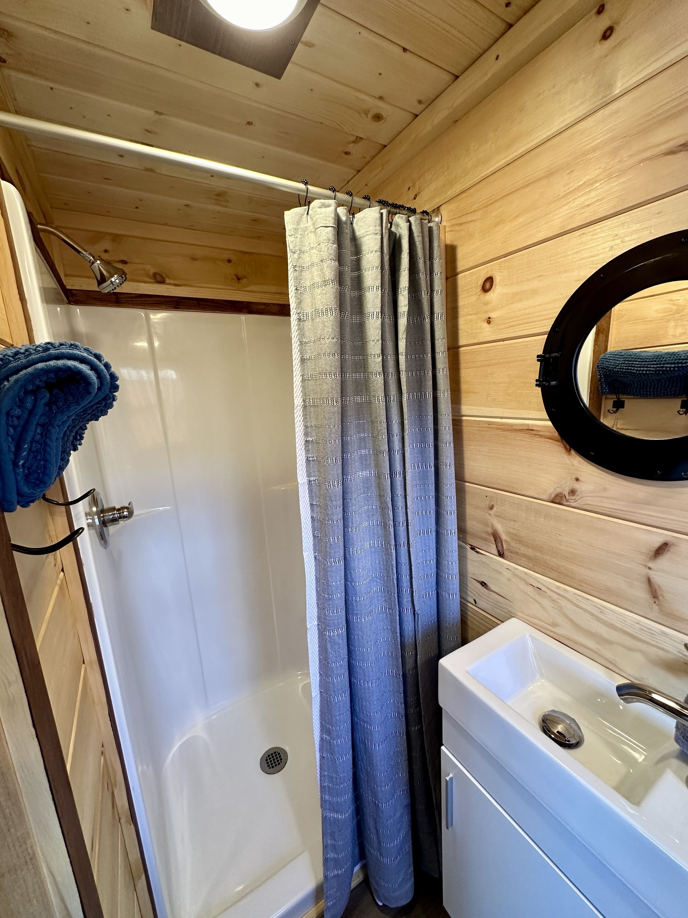 Un baño con paneles de madera, una ducha, un lavabo y un perchero para toallas.