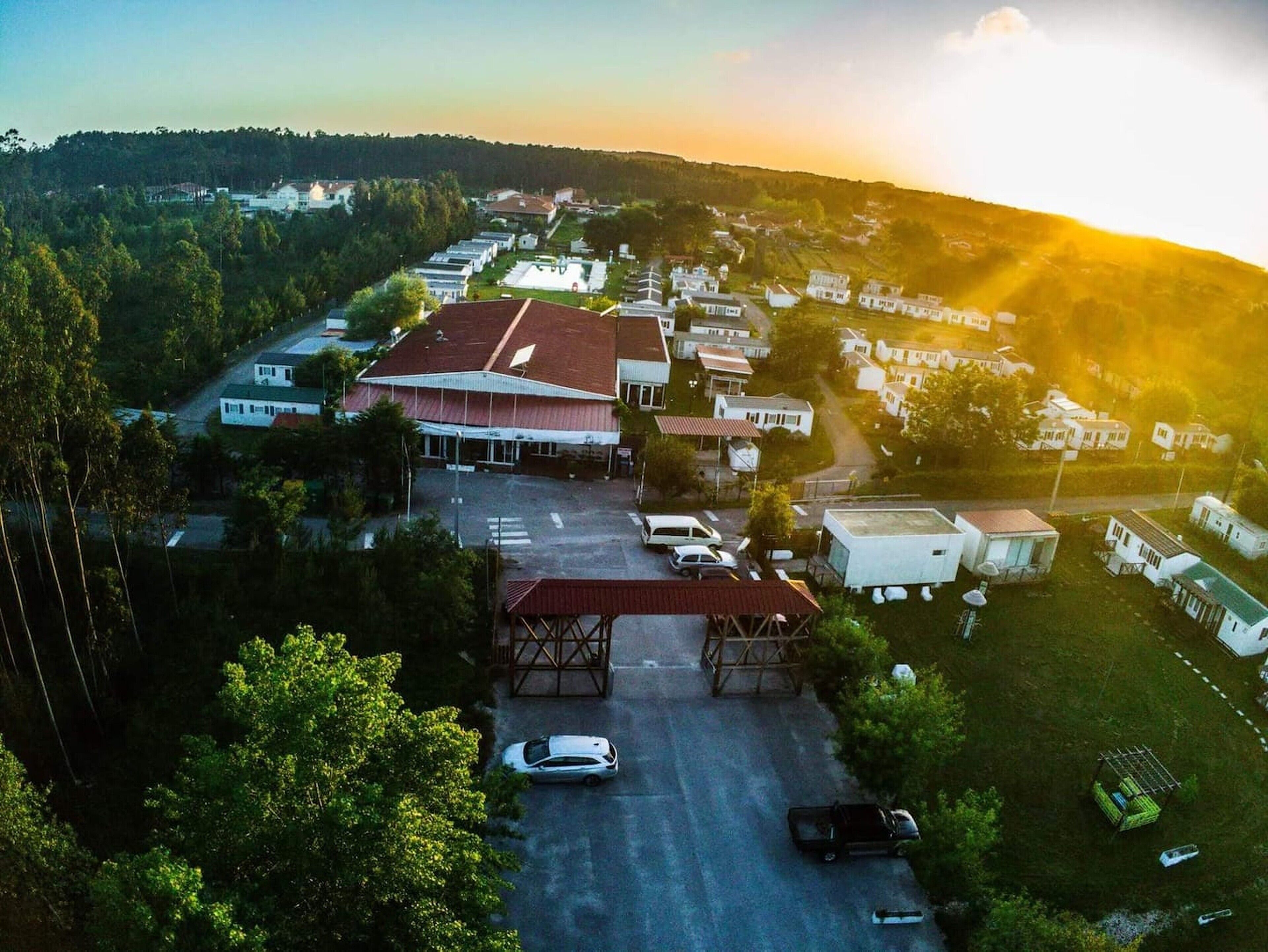 An aerial view of a residential area with houses, a large building with a red roof, and a parking lot.