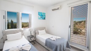 A hotel room with two beds, a small table, a nightstand, and a window with a view. - Villa Prcv614, Luxury 6bdr Protaras Villa with Pool and Panoramic Sea views (Ayia Napa)