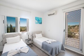 Une chambre d’hôtel avec deux lits, une petite table, une table de chevet et une fenêtre donnant sur un beau paysage.