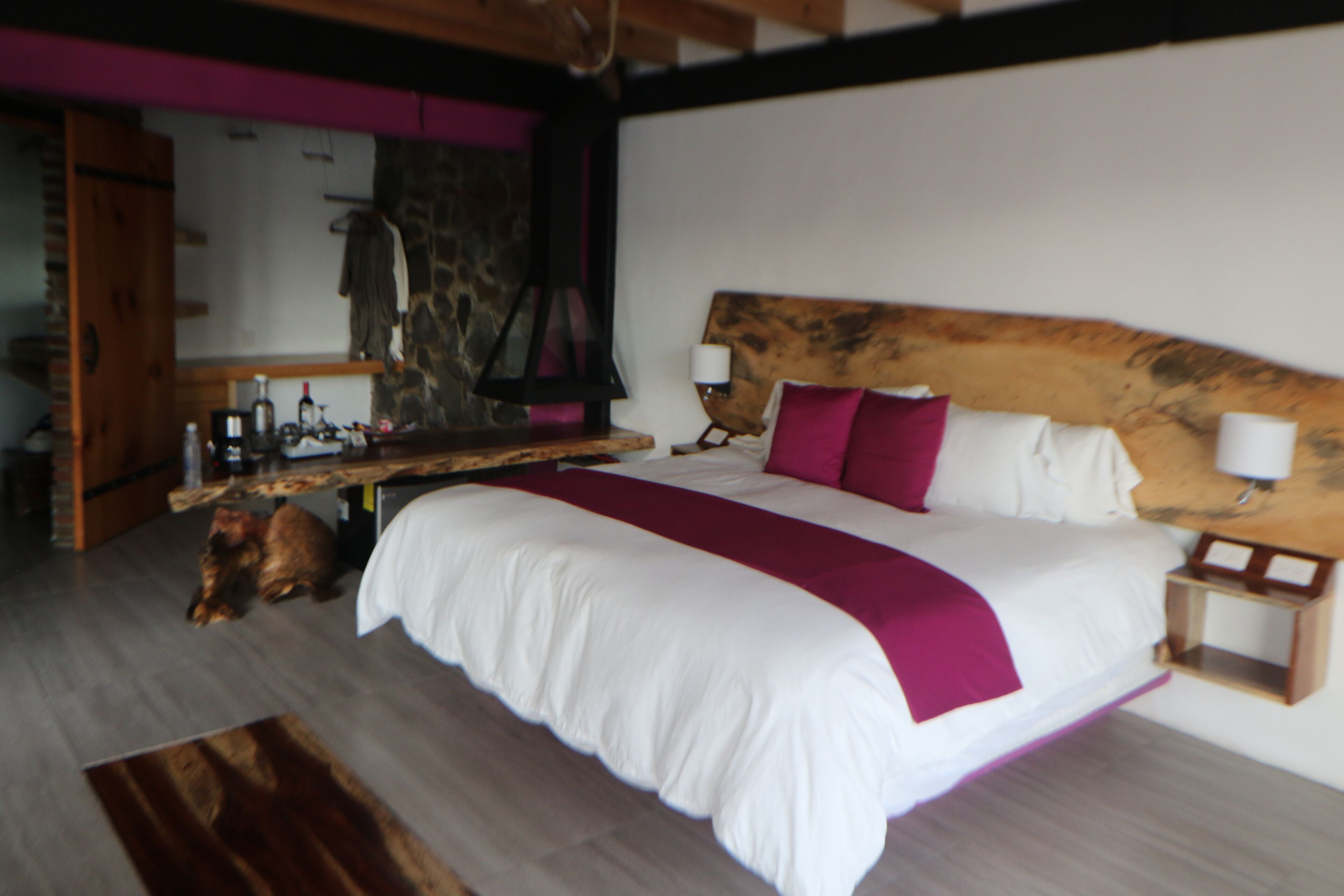 Un dormitorio con una cama grande, cabecera de madera y una mesita de noche con lámpara.