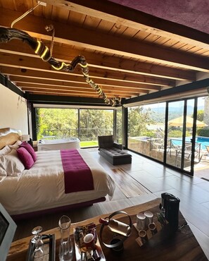 A spacious bedroom with a large bed, a view of a swimming pool, and a wooden ceiling. - Casa Acento (Valle de Bravo)
