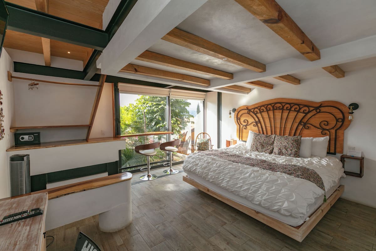 Un dormitorio moderno con cabecera de madera, una cama grande, un escritorio y una silla.