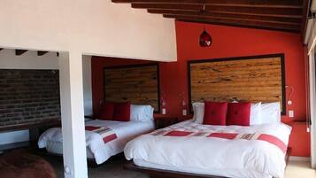 A room with two beds, red walls, wooden headboards, and a brick wall in the background.