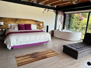 A bedroom with a bed, a sofa, a bathtub, and a view of greenery outside. - Casa Acento (Valle de Bravo)