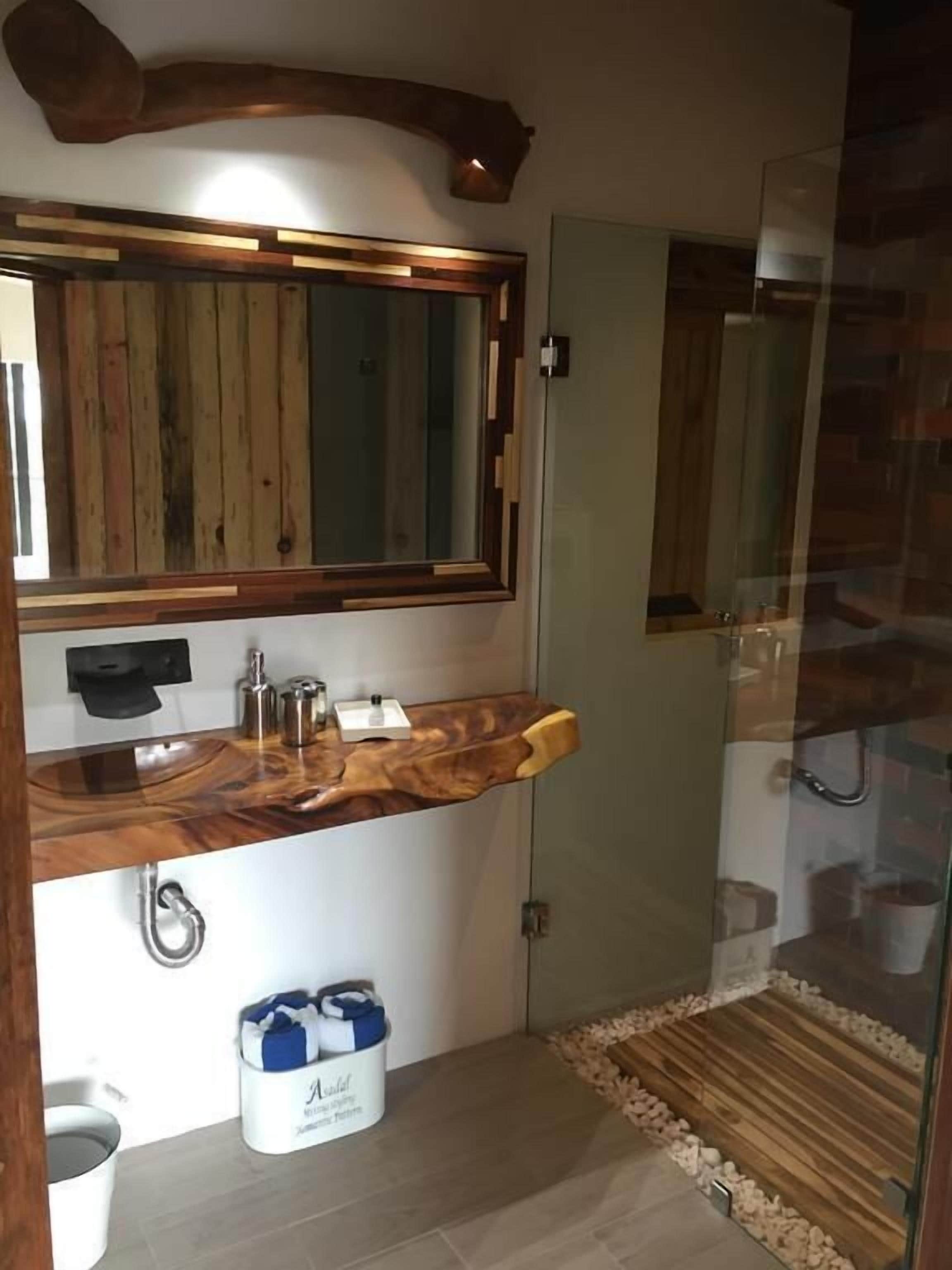 Un baño con tocador de madera, un espejo grande y cabina de ducha de vidrio.