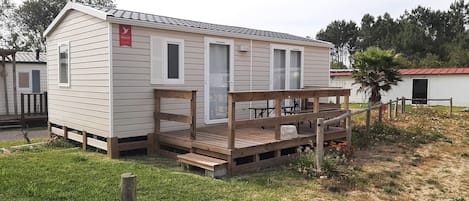 A small, single-story mobile home with a porch and a deck.