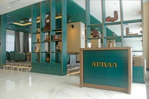 Un hall d’hôtel moderne aux murs de couleur turquoise, doté d’un sol en marbre et d’un comptoir d’accueil arborant la marque « AUTMAN ».