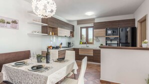 Una cucina moderna con zona pranzo, dotata di isola centrale, mobili in legno e lampadario.