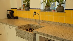 A kitchen with a granite countertop, a built-in sink, a coffee maker, and potted plants on the windowsill. - Holiday Home in Haaren Near De Efteling (Haaren)