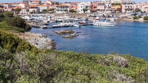 A coastal town with a marina filled with boats, surrounded by buildings with red-tiled roofs.