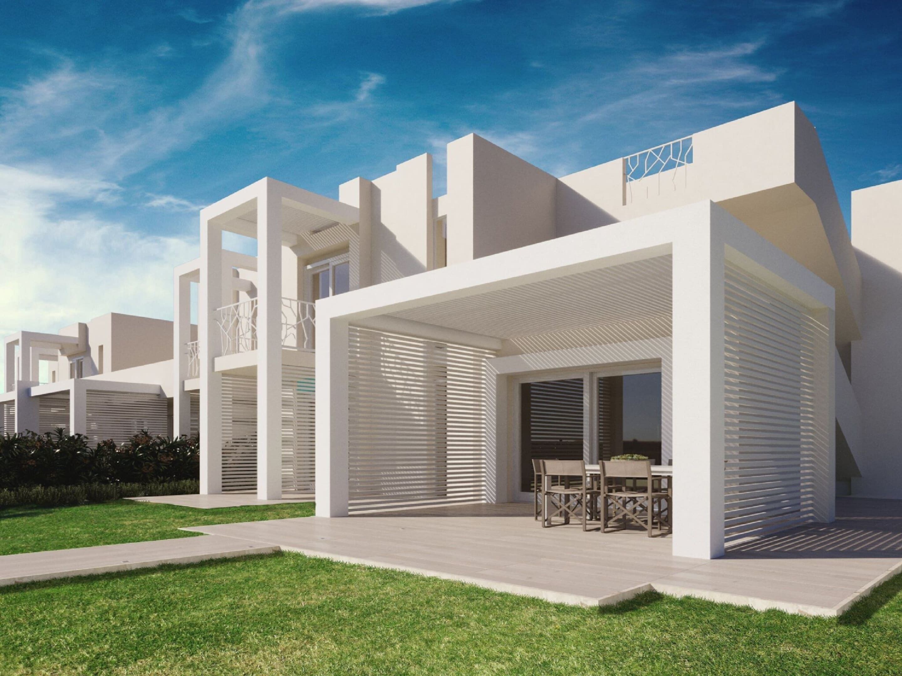 A modern residential building with a flat roof, large windows, and a covered outdoor seating area.