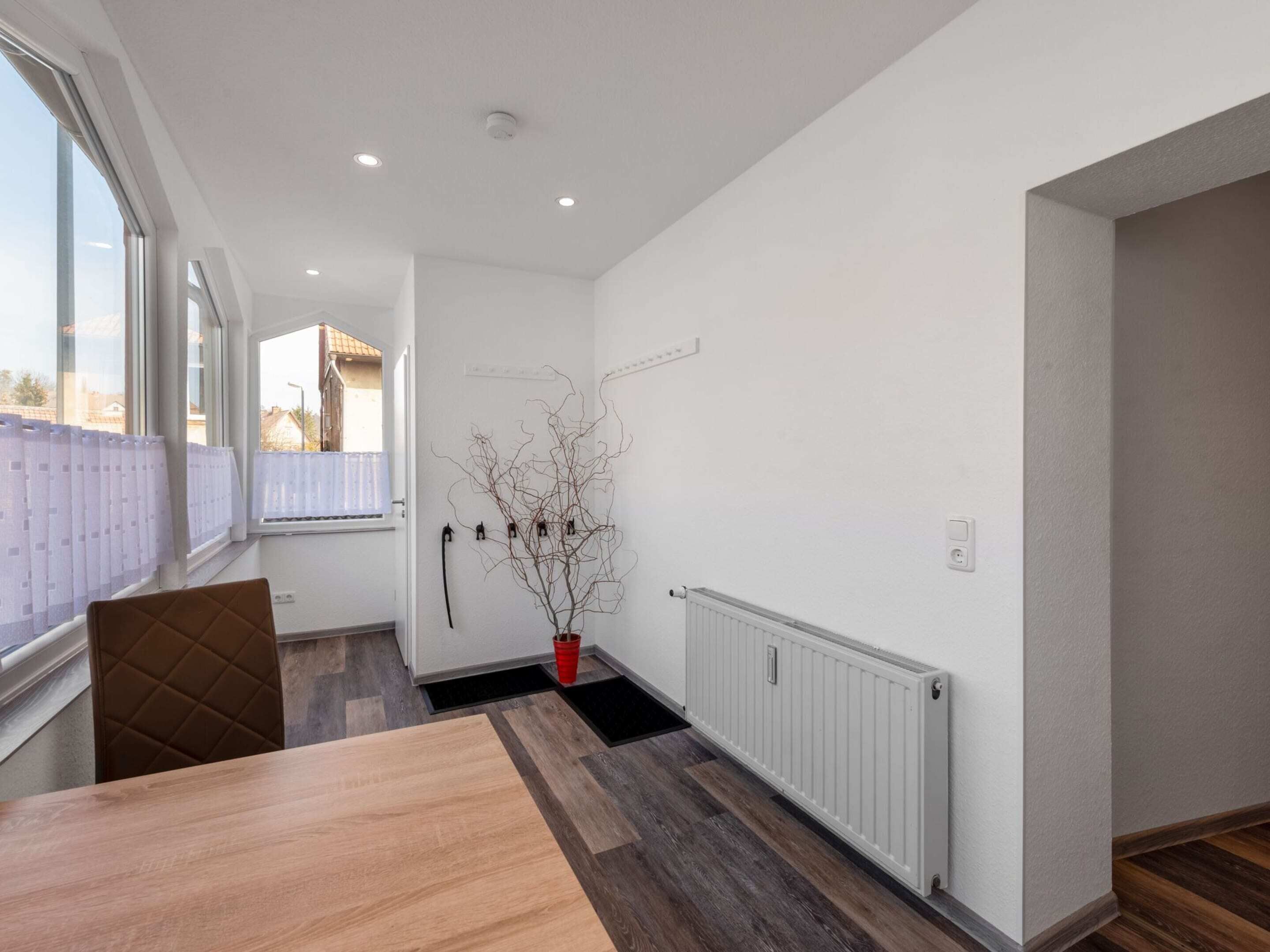 Une pièce moderne et bien éclairée, dotée d’une grande fenêtre, d’une table en bois et d’un radiateur.