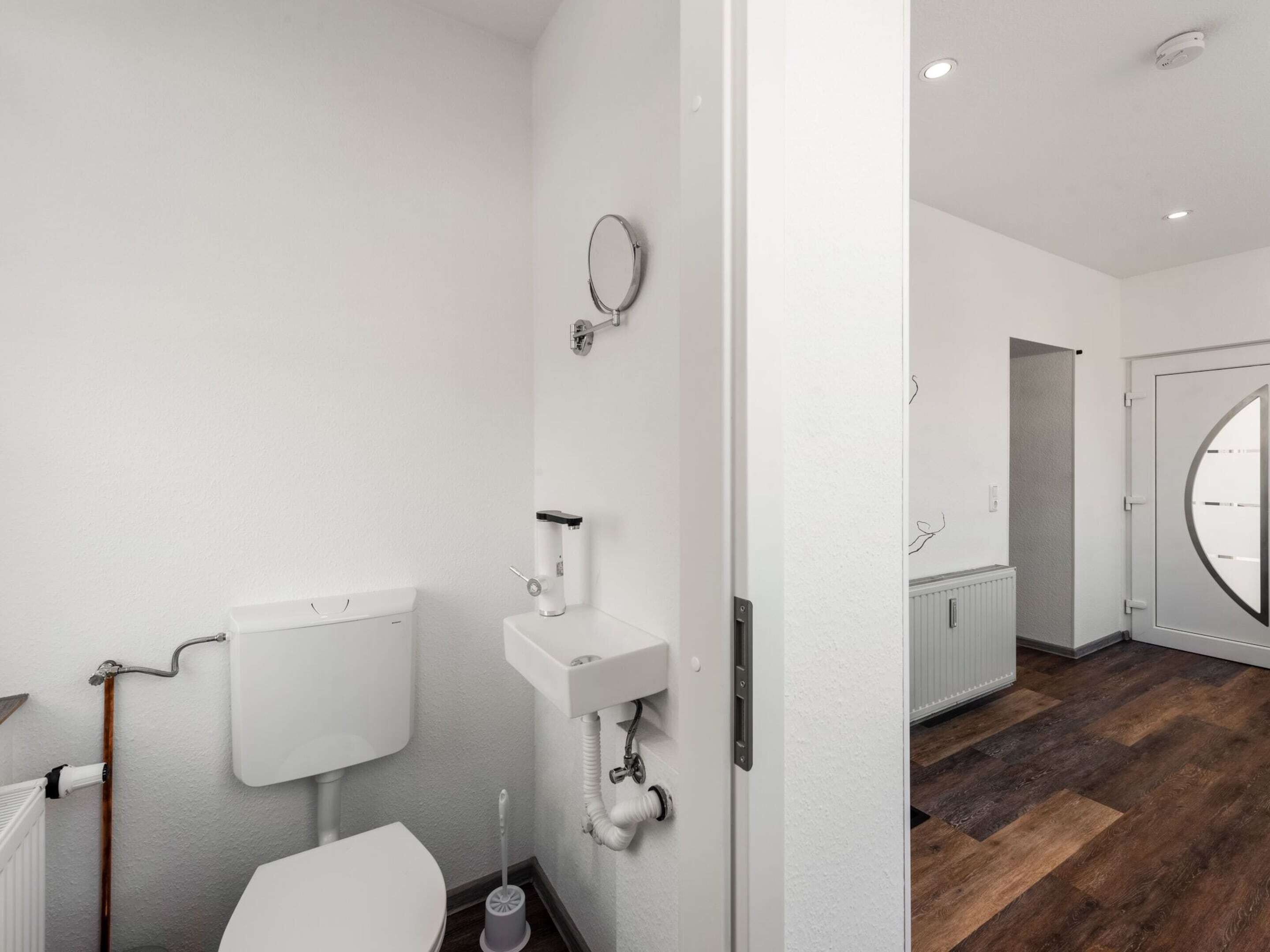 A modern bathroom with a toilet, sink, and mirror.