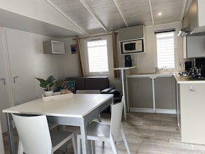 A compact kitchenette with a microwave, a sink, and a coffee maker. There is a dining area with a table and chairs. - Chalet Near Antwerp With Pool Access (Rijkevorsel)