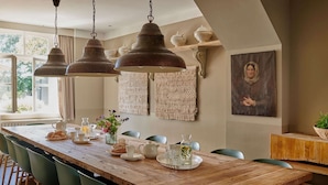 A long wooden dining table with chairs, hanging pendant lights, and a view of the outdoors. - Sprawling Farmhouse in Baarlo With Hot Tub, Private Garden (Baarlo)